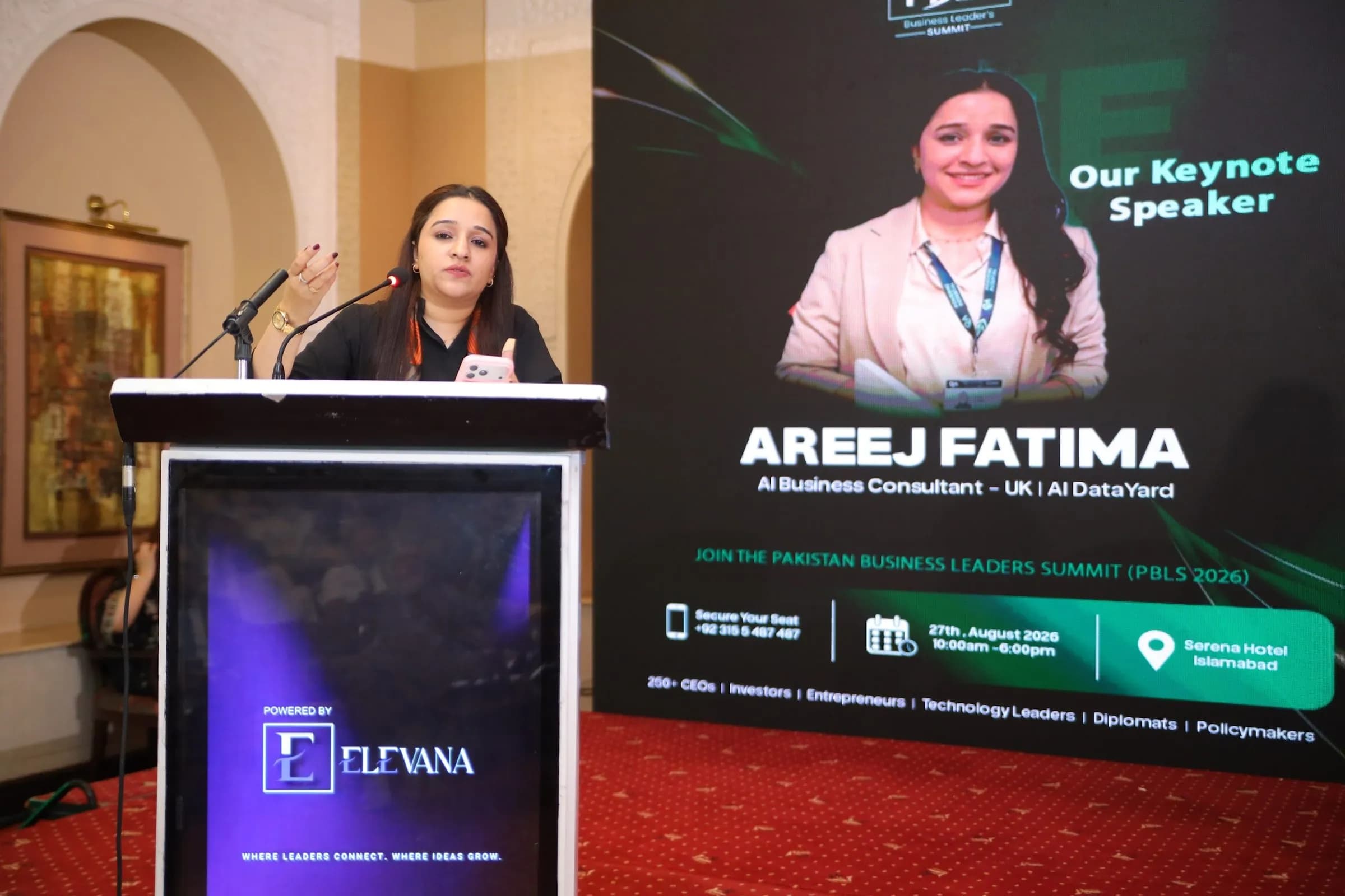 A keynote speaker at the podium beside her speaker screen at PBLS Serena Islamabad
