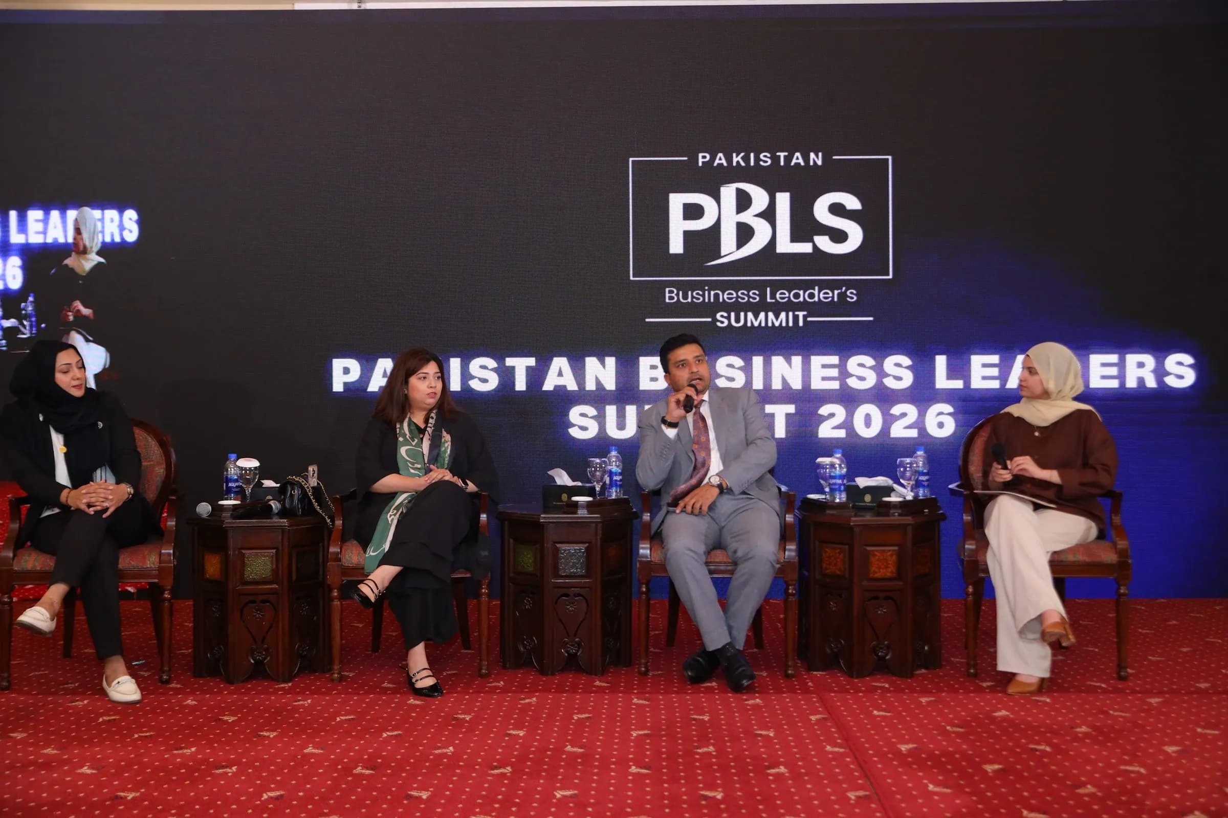 A panel discussion on stage in front of the PBLS summit backdrop at PBLS Serena Islamabad